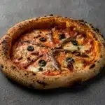 Homemade Napoli pizza topped with anchovies, olives, and fresh tomato sauce at Secret Oven restaurant